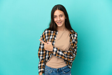 Young French woman isolated on blue background pointing to the side to present a product