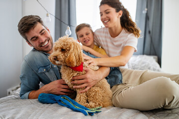 Happy young friendly family spending fun times together and cuddling with their pet at home