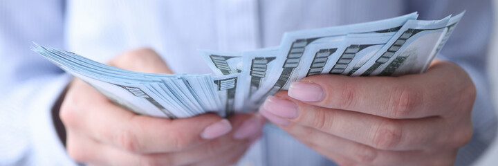 Woman counting currency american dollars at workplace closeup