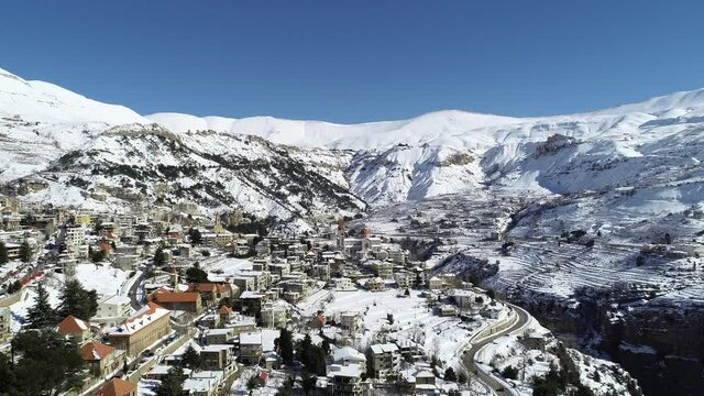 Aerial footage of the mountains covered by snow. Beautiful winter scene. Beautiful village in the middle east region. Lebanese village in winter season. Sunny weather near the ski resort. Rural scene