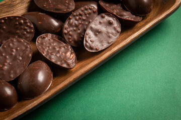 Mini halves of crunchy easter eggs on a wooden basket on a green background.