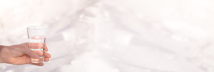 . Glass of clean blue water on a snowy background. The concept of clean, healthy water. World Water Day.