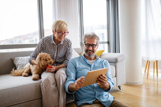 Lovely smiling mature couple having fun while using tablet at home