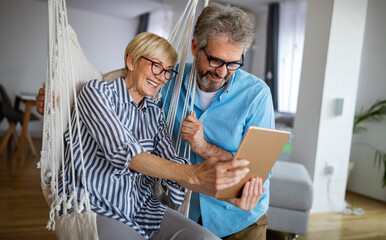 Obraz premium Happy smiling mature couple using digital tablet at home