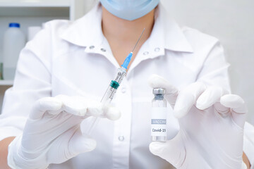 COVID-19 vaccine in researcher hands, female doctor holds syringe and bottle with vaccine for coronavirus cure.