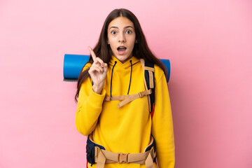 Young mountaineer girl with a big backpack isolated on pink background intending to realizes the solution while lifting a finger up