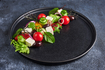 Fresh greek salad with tomato, cucumber, bel pepper , olives and feta cheese on black plate, close...