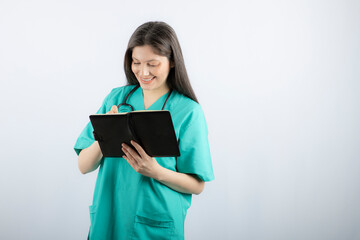 Photo of a young female doctor standing with notebook and pencil