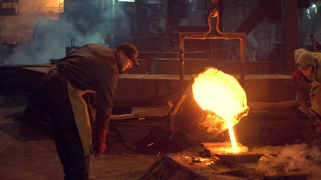 Workers pour hot metal into molds.Industrial worker casting metal at metallurgical factory. Molding molten metal at industrial plant. Manufacturing iron products in heavy industry.Video 4 k.