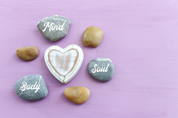 Obraz premium zen stones with the words Mind body soul. purple wooden background
