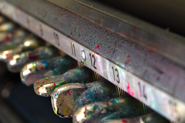 Multicolored drops of paint on the tuners of the old printing press. Close-up of a fragment of an...