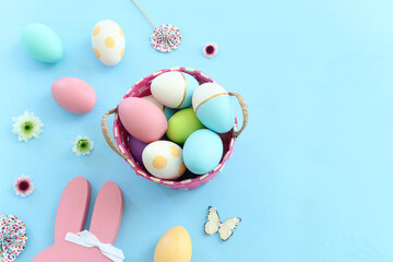 Cute bunny next to easter colorful eggs over pastel background