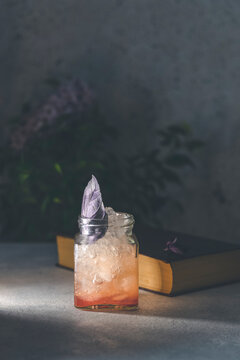 Picnic smash. Refreshing cold summer cocktail with grapefruit and  garnish by violet red basil leaves. Served in glass jar with crashed ice. Atmosphere of romantic date.