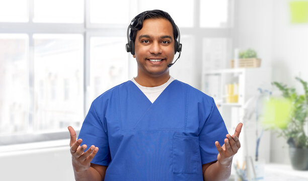 Medicine, Profession And Healthcare Concept - Happy Smiling Indian Doctor Or Male Nurse With Headset Over Medical Office At Hospital Background