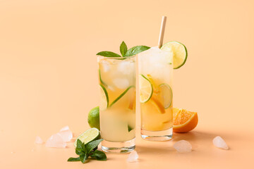 Two summer cold lemonade or mojito cocktail with orange and lime slice on color beige background....