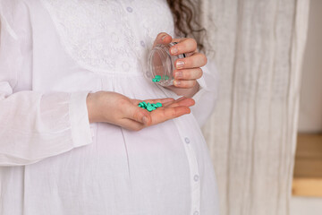Pregnant woman with big belly holding medical pills, tablets, supplements, homeopathy. concept of using vitamins during pregnancy, health expecting for newborn. closeup