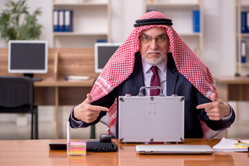 Aged arab businessman employee holding case with banknotes in th