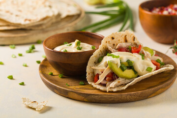 Mini tortillas with tomato salsa, avocado and boiled chicken. Front view.