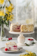 Napoleon puff cake with berry filling on a wooden stand with a cut piece on a plate.