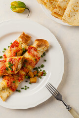 Baked pancakes with chicken in tomato sauce.