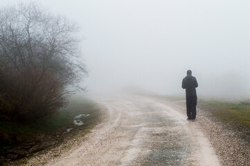 Persona, un hombre en un camino en la naturaleza, en el campo, un dia con mucha niebla.