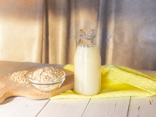Glass bottle with vegetable oat milk and oat flakes. Lactose-free milk, vegetarianism.