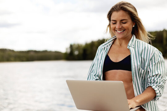 Happy woman with laptop at boat deck