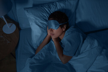 people, relax and comfort concept - young african american woman in eye mask sleeping in bed at...