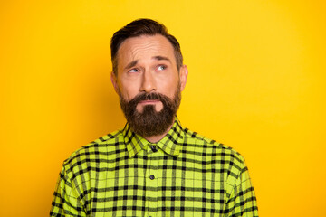Photo of mature handsome man unhappy sad upset think dream questioned look empty space isolated over yellow color background