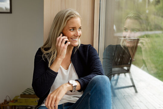 Blond woman using mobile phone and looking through window