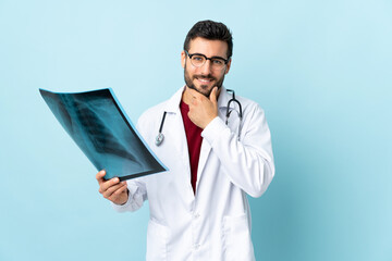 Professional traumatologist holding radiography isolated on blue background laughing