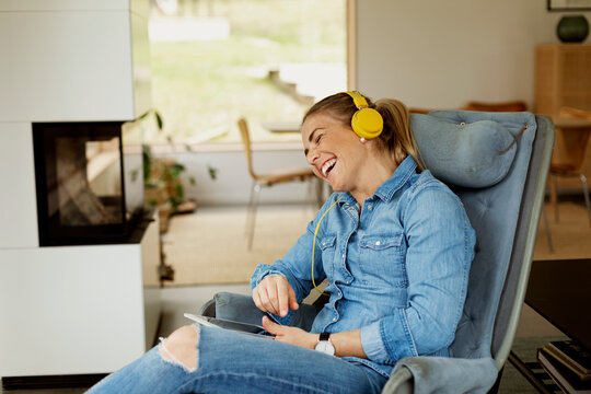 Woman sitting in armchair and using digital tablet