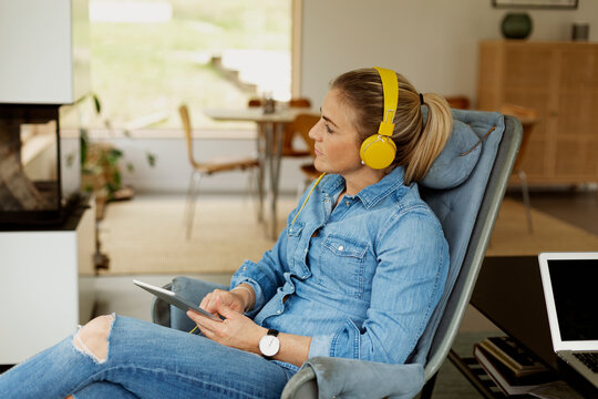 Woman sitting in armchair and using digital tablet