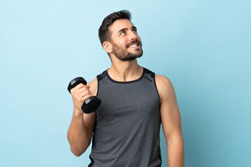 Young sport man with beard making weightlifting looking up while smiling