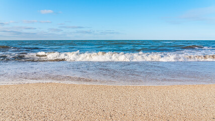 Fototapeta na wymiar Empty beach with yellow sand and blue waves, quarantine at the resort