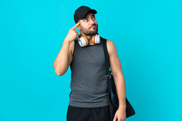 Young sport man with sport bag isolated on blue background making the gesture of madness putting...