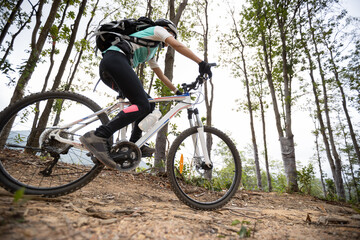 Fototapeta premium Woman cyclist cycling on mountain top forest trail