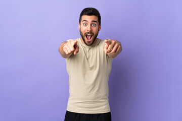 Naklejka premium Young handsome man with beard over isolated background surprised and pointing front
