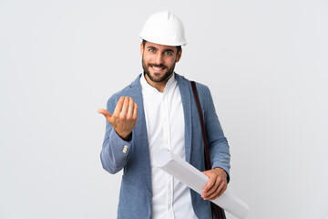 Young architect man with helmet and holding blueprints isolated on white background inviting to...