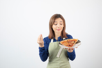 Portrait of woman in kitchen apron showing plate of pizza on white background