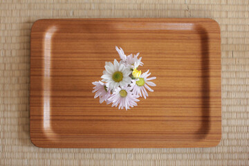 simple white, yellow and pink chrysanthemum flower arrangement with wood plate on tatami