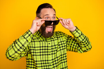 Profile side photo of excited man happy amazed surprised hands touch sunglass look empty space isolated over yellow color background
