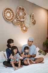 happy asian family with two children spend their time together in the bedroom