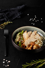 chinese noodles with vegetables and meat in a plate on black background