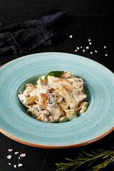 chinese noodles with vegetables and meat in a blue plate on black background