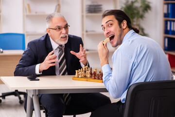 Two businessmen playing chess in the office