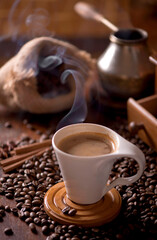 cup of coffee and coffee beans in a sack on dark background, top view