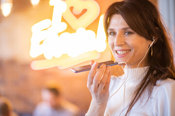 A beautiful young European woman with headphones and a phone in her hands is listening to a new...