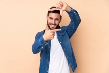 Caucasian handsome man isolated on beige background focusing face. Framing symbol