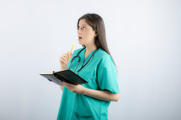 Photo of a young female doctor standing with notebook and pencil